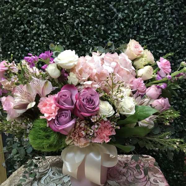Pink and purple mixed flower arrangement in a ribbon-tied vase