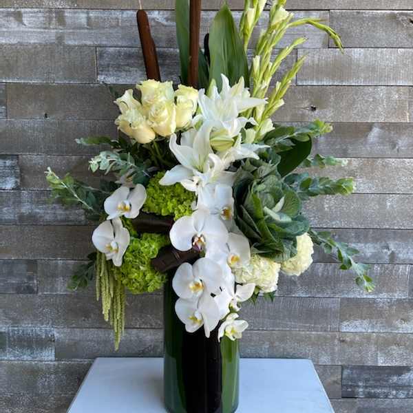 White orchids, lilies, and roses arranged in a tall vase