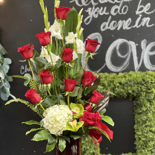 Tall arrangement of red roses and white flowers in a glass vase