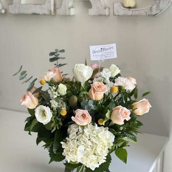 Bouquet of peach and white roses with hydrangea in a glass vase