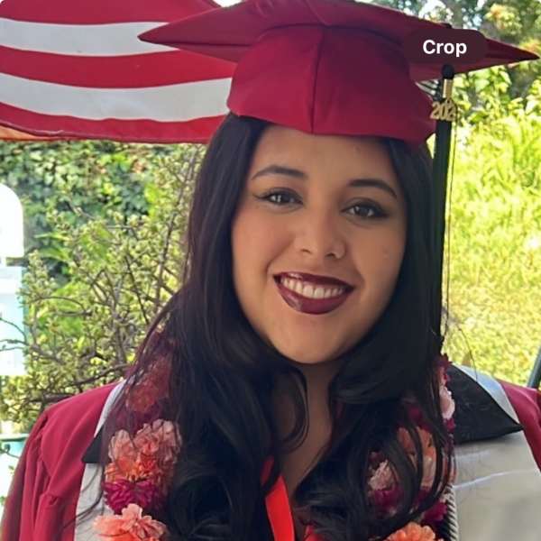 Graduate in maroon cap and gown with a flower lei