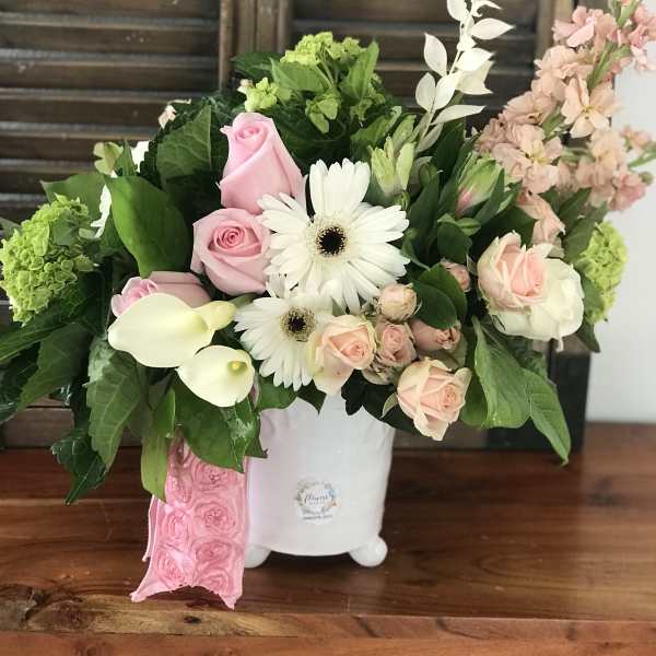 Pink roses and white daisies arranged in a white vase