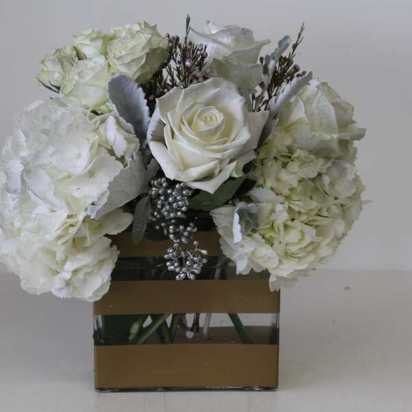 White roses and hydrangeas arranged in a square glass vase