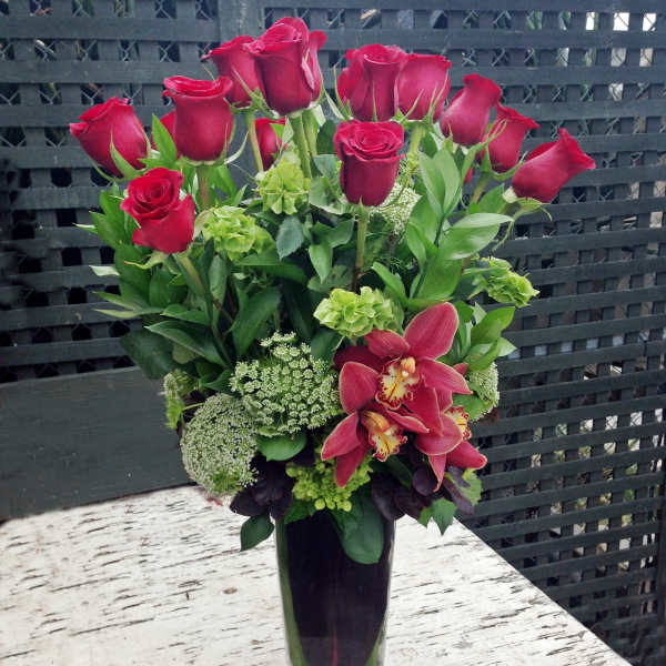 Red roses and pink orchids in a tall glass vase