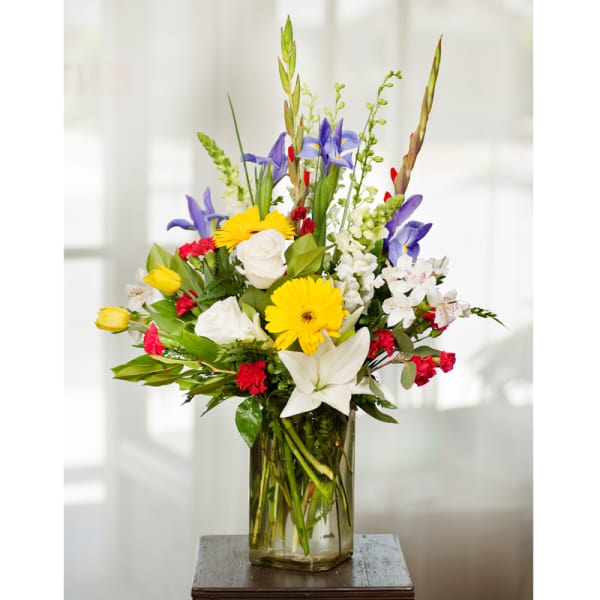Mixed bouquet of lilies, roses, and daisies in a glass vase