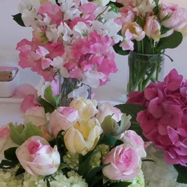 Pink and white floral arrangements with roses and hydrangeas in glass vases