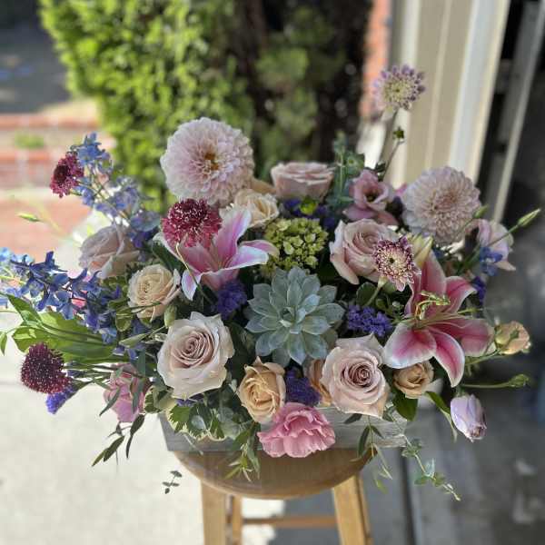 Mixed pastel bouquet with roses, lilies, and dahlias in a low container