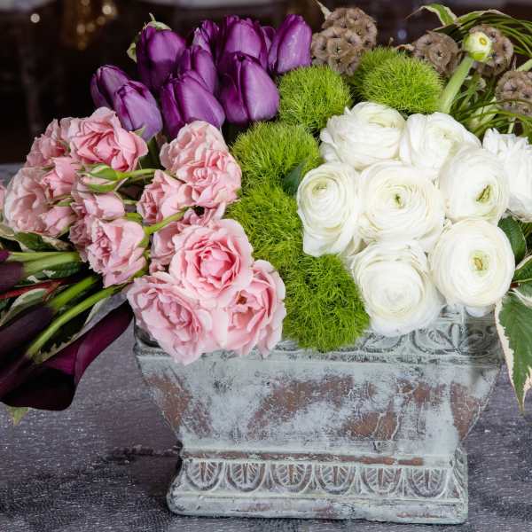 Arrangement of pink, purple, and white flowers in a weathered rectangular planter