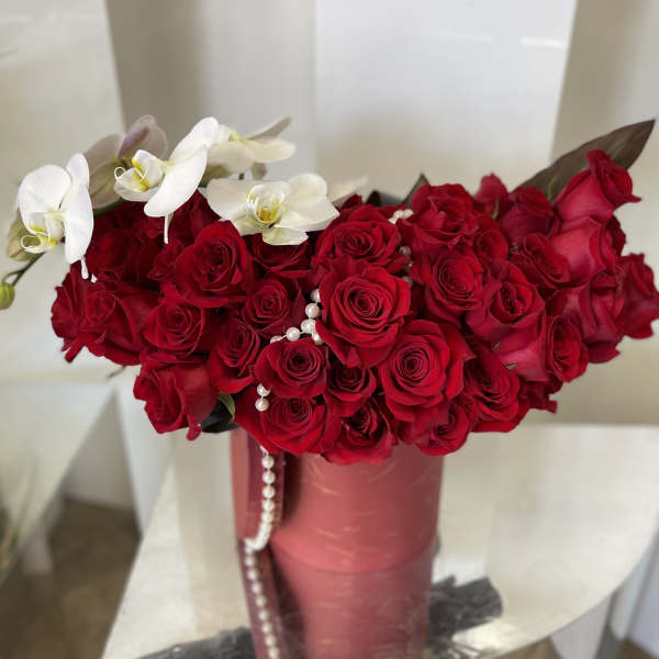 Red rose bouquet with white orchids in a pink vase