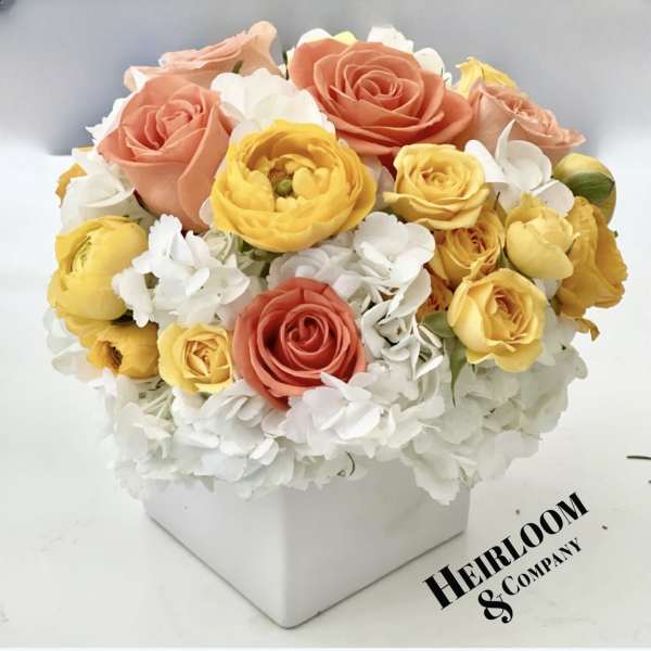 Peach, yellow, and white roses in a white square box