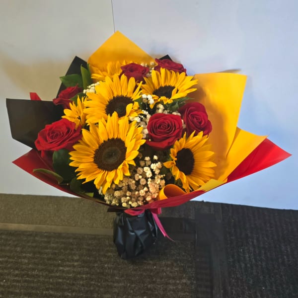 Bouquet of sunflowers and red roses wrapped in black, yellow, and red paper