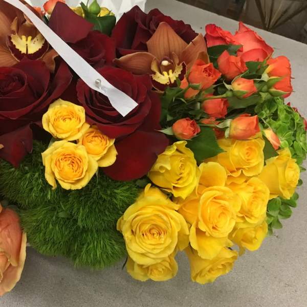 Mixed bouquet of roses and orchids in red, peach, yellow, and orange