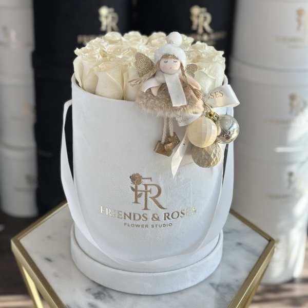 Cream roses in a white round box with a small angel ornament.