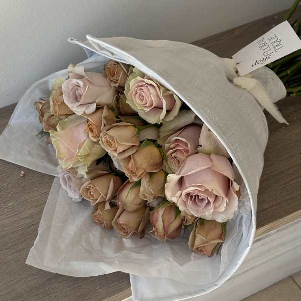 Bouquet of pale pink and peach roses wrapped in white paper