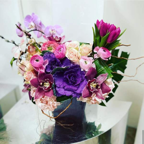 Purple and pink floral arrangement in a dark vase