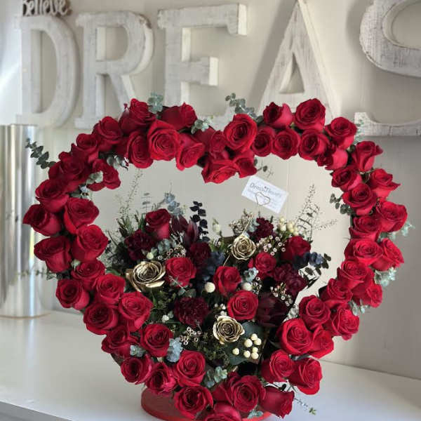 Heart-shaped rose arrangement with red and burgundy blooms