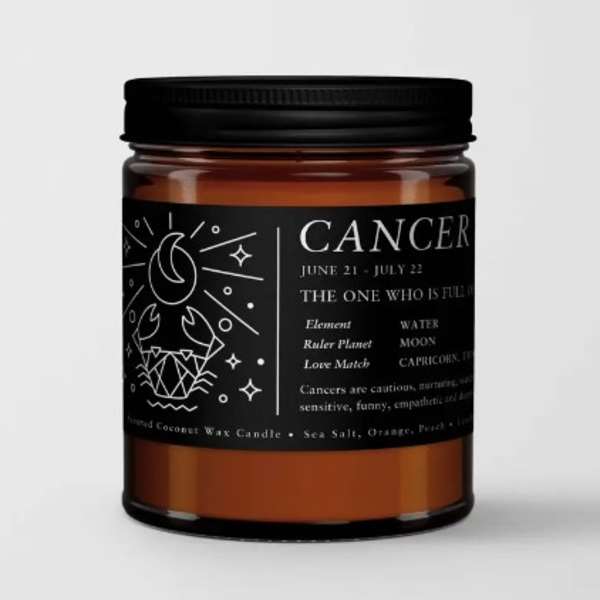 Amber jar candle with a black label reading Cancer