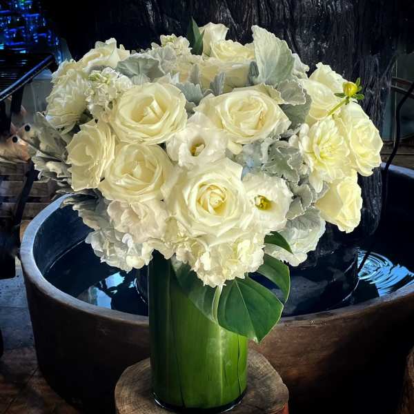 White roses and pale blooms arranged in a tall green vase