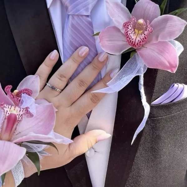 Pink orchid corsage and boutonniere with lavender ribbon on a suit jacket