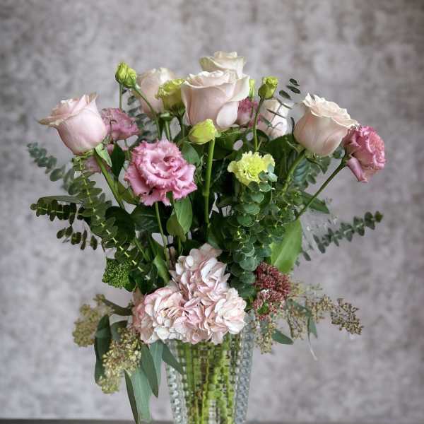 Pink roses and carnations in a clear glass vase