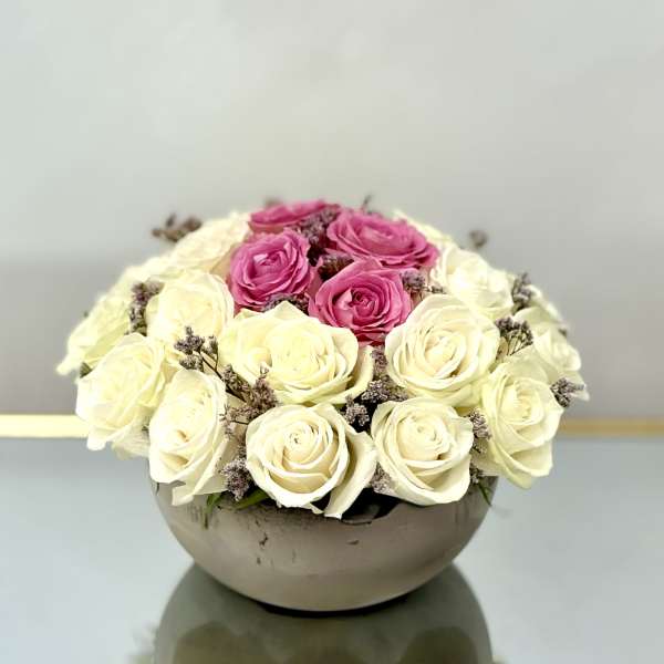 Pink and white roses arranged in a low round bowl