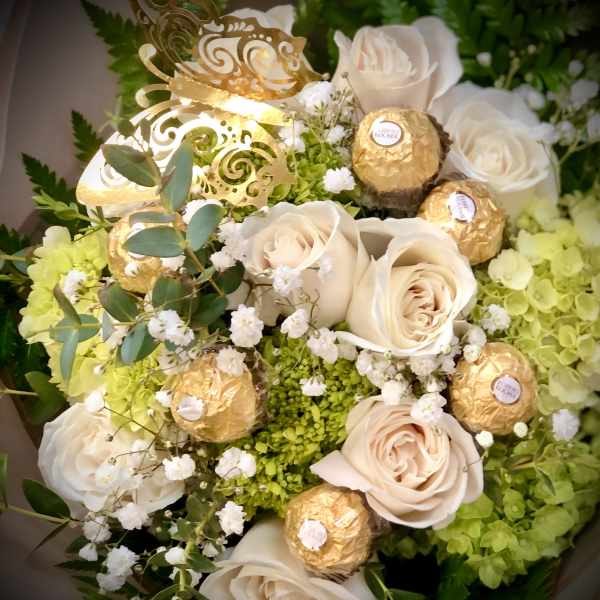Bouquet of cream roses with gold-wrapped chocolates and white filler flowers