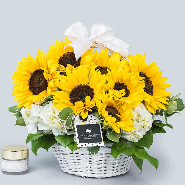 Basket of sunflowers with white hydrangeas and a white bow