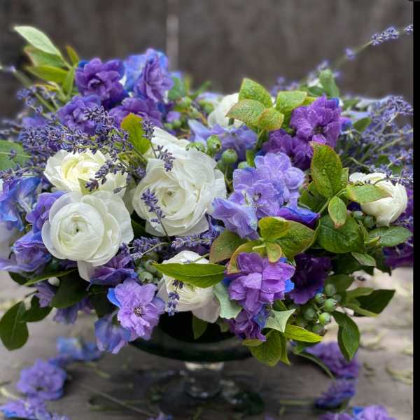 Purple and white floral arrangement in a dark vase
