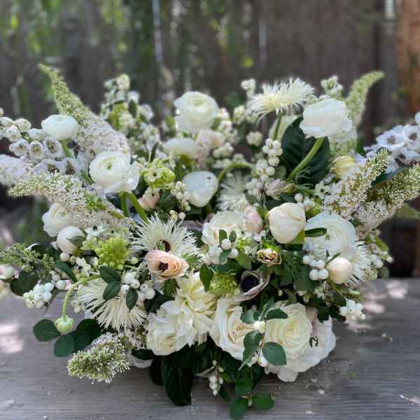 Large white floral arrangement with mixed blooms and berries