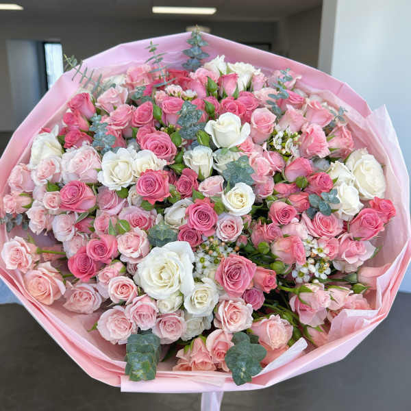 Large bouquet of pink and white roses wrapped in pink paper