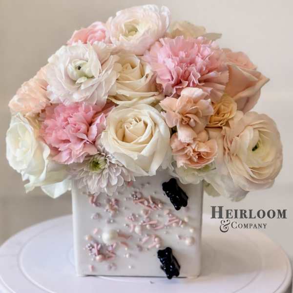 Pink and white bouquet in a decorated square vase