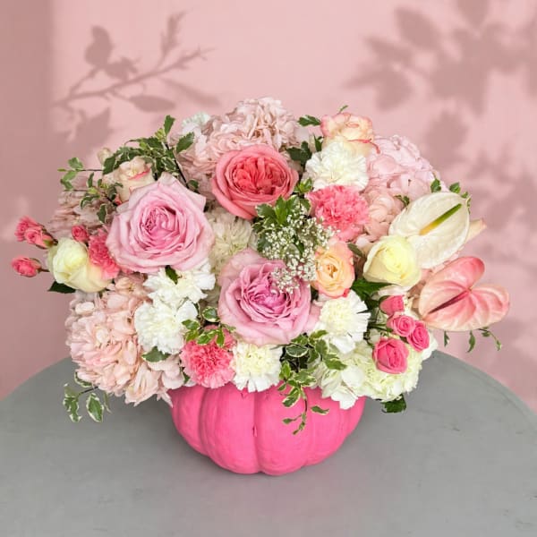 Pink and white floral arrangement in a bright pink pumpkin vase