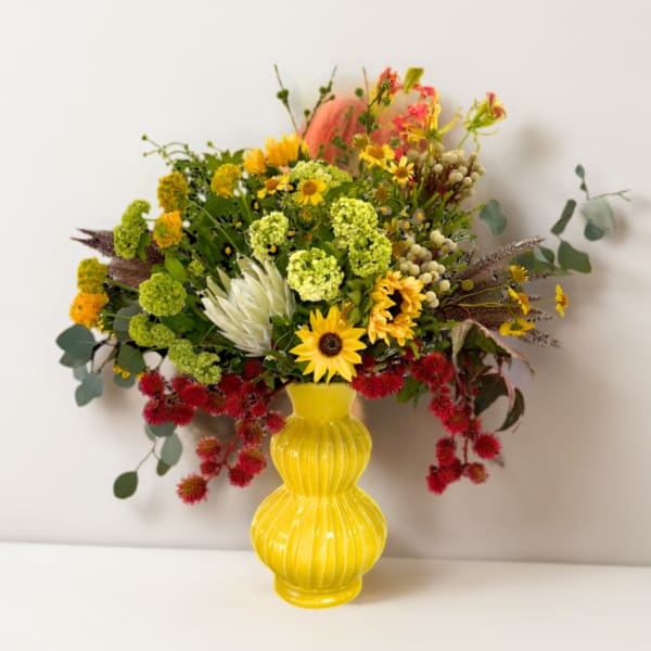 Mixed bouquet in a yellow vase with sunflowers and red blooms