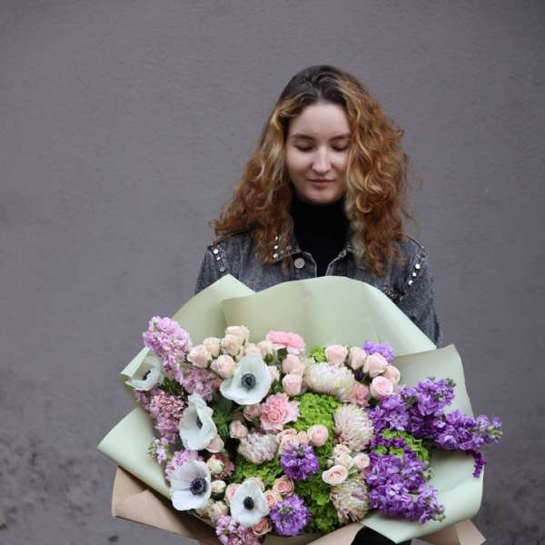 Woman holding a large pastel bouquet of pink, purple, and white flowers