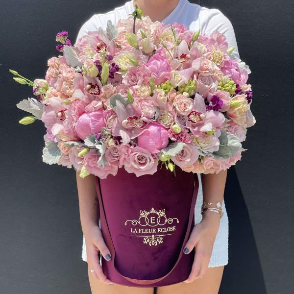 Large pink bouquet in a burgundy hatbox held by a person