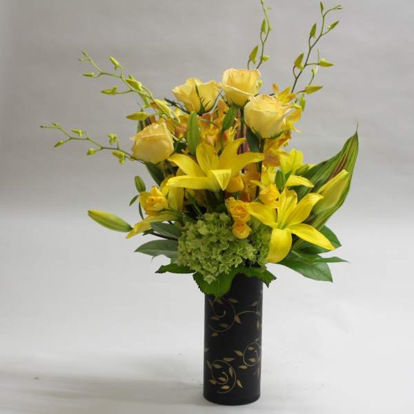 Yellow roses and lilies arranged in a black vase
