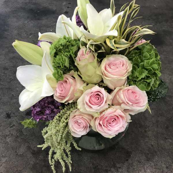 Pink roses and white lilies arranged in a low glass vase