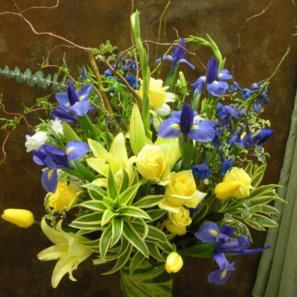 Blue irises and yellow roses in a tall glass vase