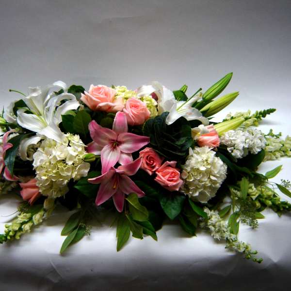Low floral centerpiece with pink roses, white lilies, and hydrangeas