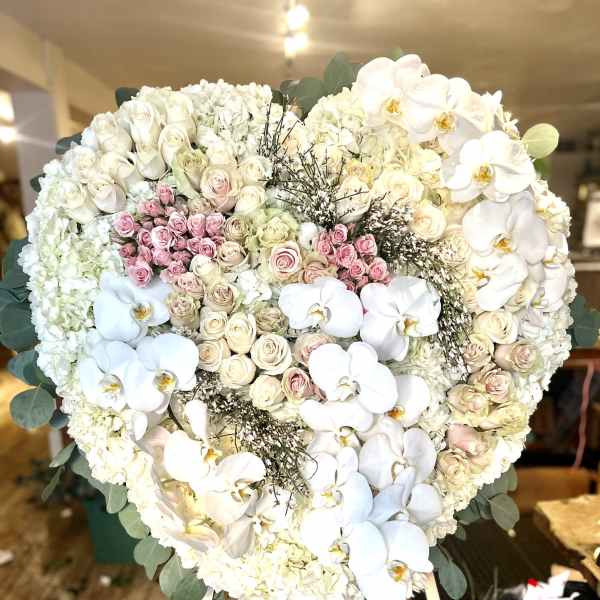 Heart-shaped white floral standing arrangement with pink roses and orchids