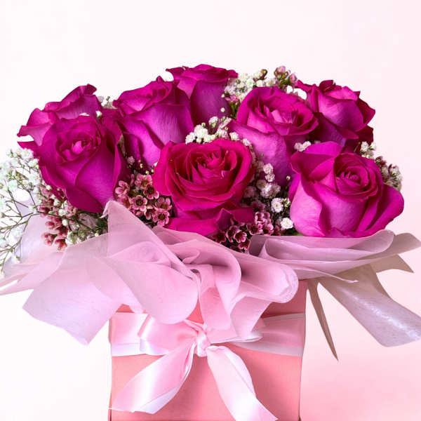 Pink roses arranged in a pink gift box with a ribbon