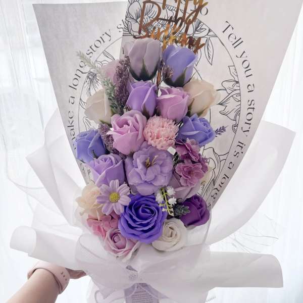 Bouquet of purple and pink roses wrapped in white paper