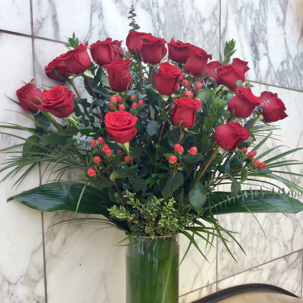 Tall vase arrangement of red roses with greenery