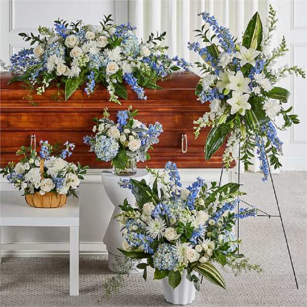 White and blue floral funeral arrangements around a casket