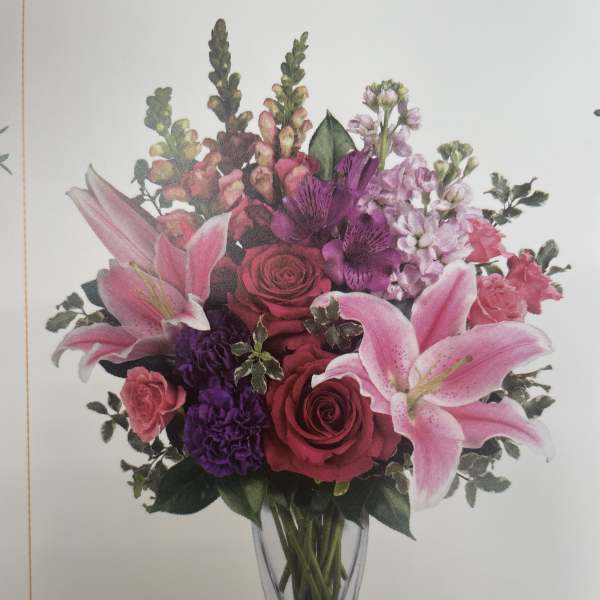Pink lilies and roses arranged in a clear glass vase
