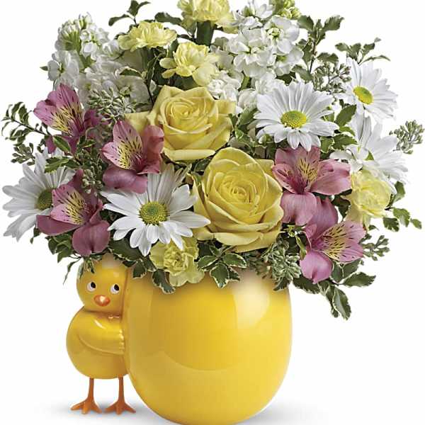Yellow mug-shaped vase with mixed flowers and a chick figurine