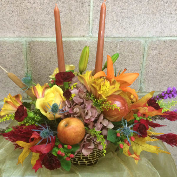 Autumn floral centerpiece with candles and fruit in a low basket