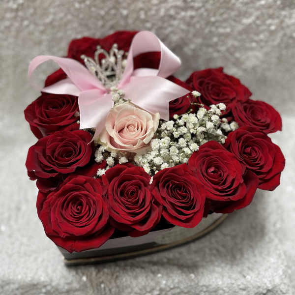 Heart-shaped box of red roses with a pink rose and ribbon bow