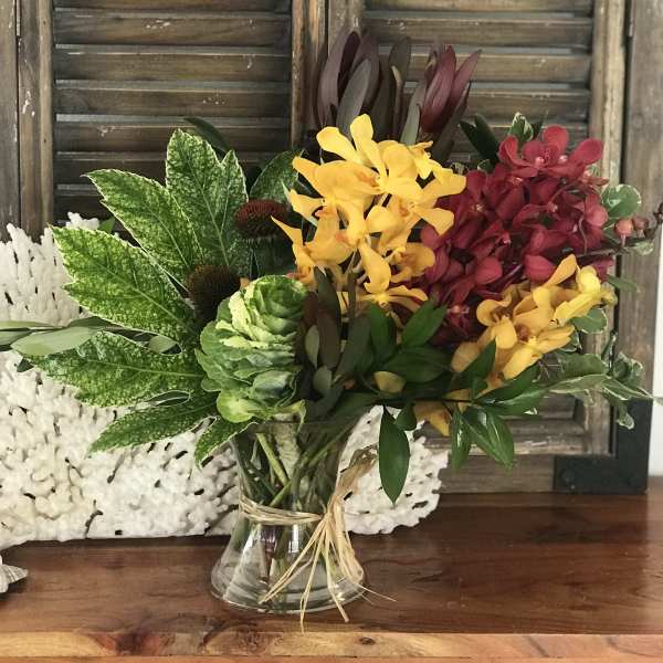 Mixed bouquet of yellow and burgundy orchids in a glass vase