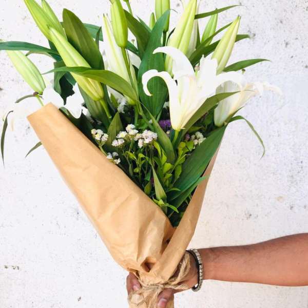 Bouquet of white lilies wrapped in brown paper